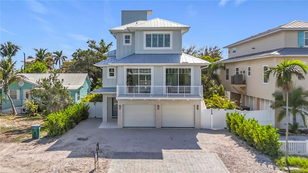 A three-story coastal house features a two-car garage, a white balcony, and light blue siding — 2918 GULF DRIVE, BRADENTON BEACH, FL