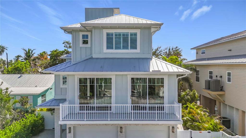 A three-story light blue house with a metal roof and a second-floor balcony — 2918 GULF DRIVE, BRADENTON BEACH, FL