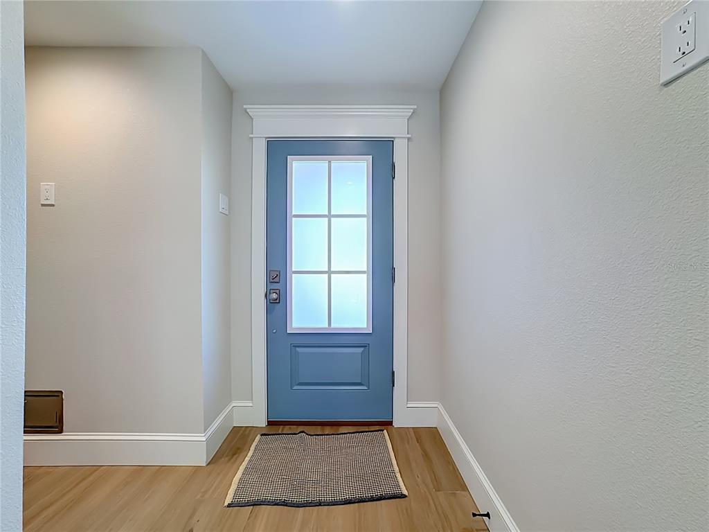 An entryway features a blue front door with a glass window and light wood flooring — 2918 GULF DRIVE, BRADENTON BEACH, FL