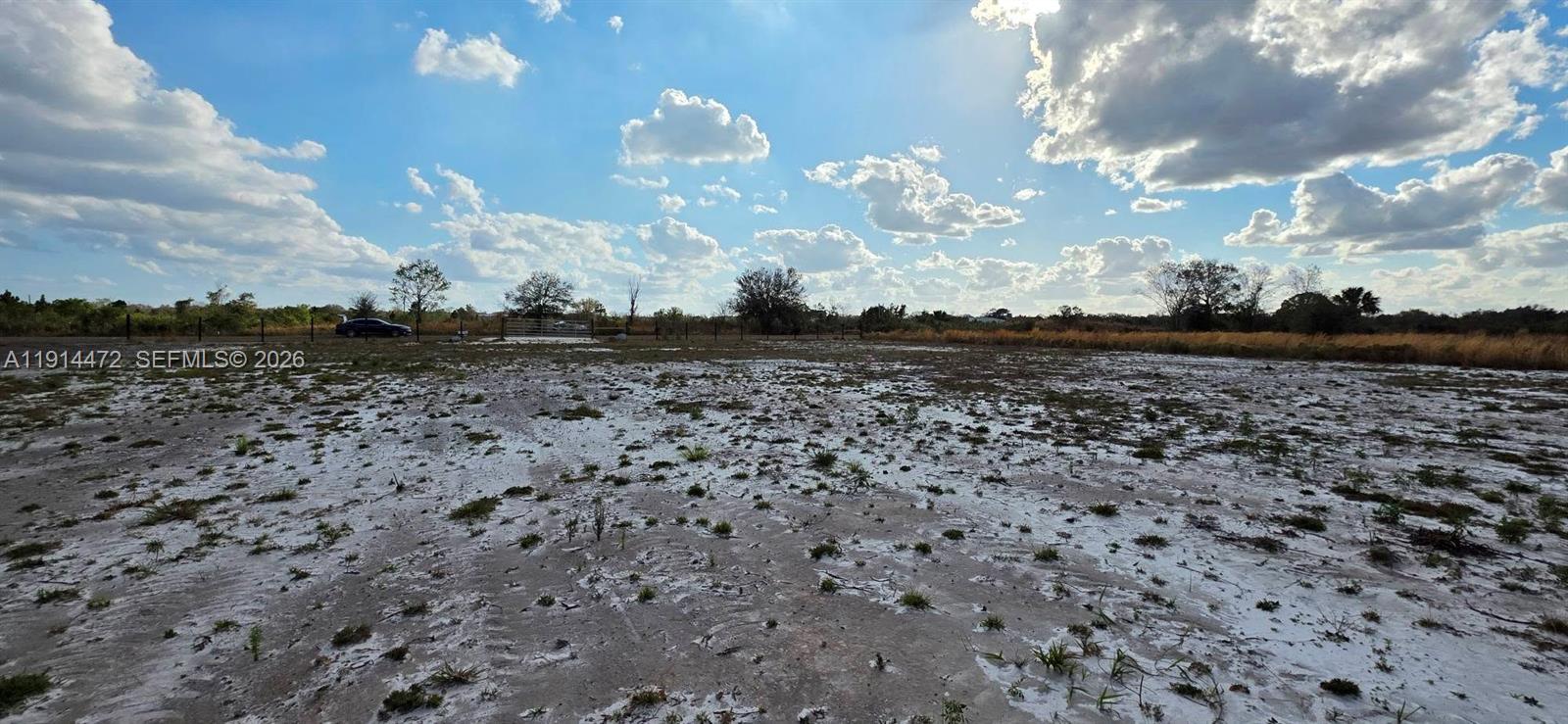 A wide, flat, sandy lot under a cloudy blue sky with a distant fence — 16525 NW 260 st, Okeechobee FL 34972, OKEECHOBEE, FL