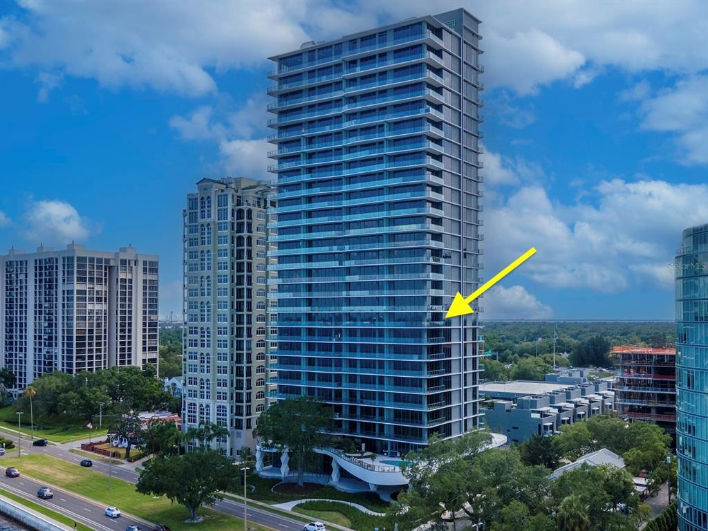 An aerial view of a modern glass high-rise building with a yellow arrow pointing outward — 3101 BAYSHORE STREET UNIT 1001, TAMPA, FL