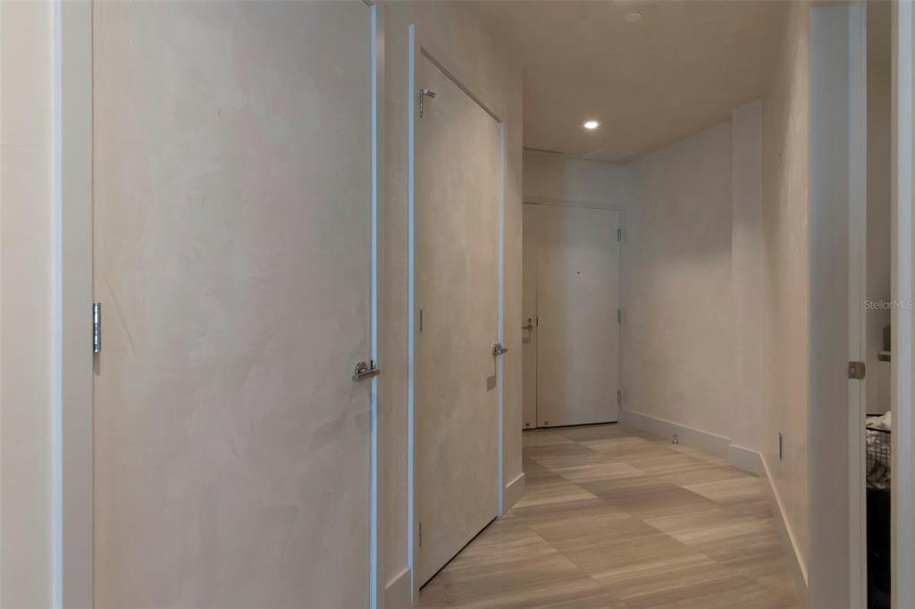 A hallway with light-colored walls, wood-look tile flooring, and several closed interior doors — 3101 BAYSHORE STREET UNIT 1001, TAMPA, FL