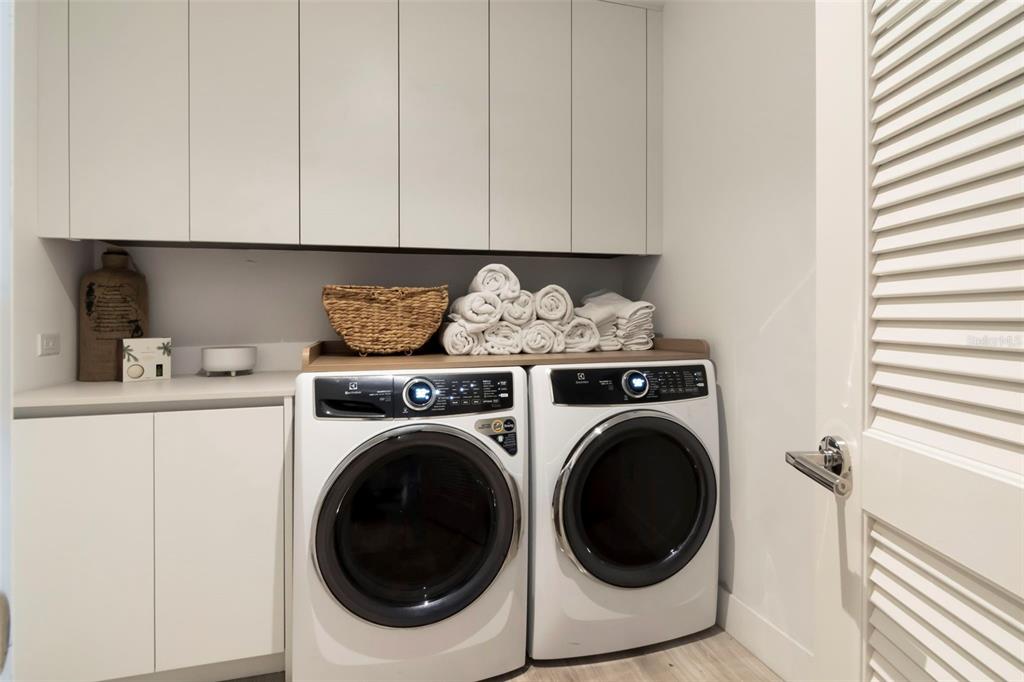 A laundry room features white cabinets, a wooden countertop, and a side-by-side washer and dryer — 3101 BAYSHORE STREET UNIT 1001, TAMPA, FL