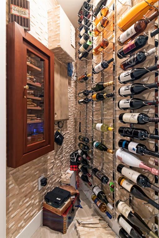A small wine cellar features a wall-mounted humidor and metal wine racks on stone walls — 3101 BAYSHORE STREET UNIT 1001, TAMPA, FL