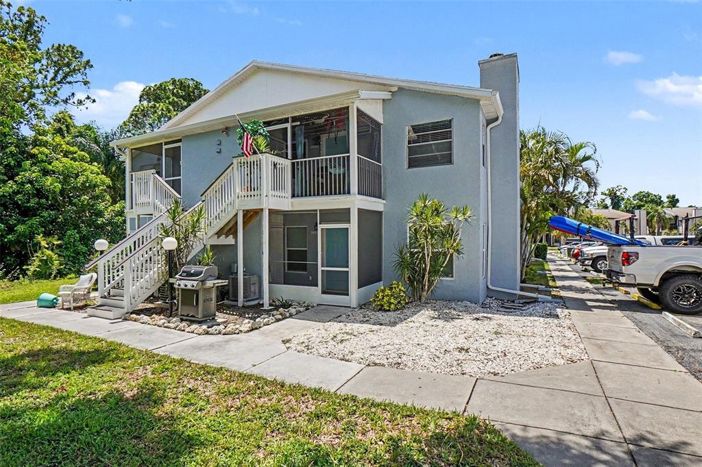 A two-story light blue residential building features outdoor staircases, screened balconies, and a gravel yard — 3606 59TH AVENUE W UNIT 3606, BRADENTON, FL