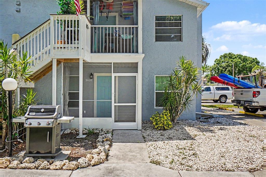 A two-story building exterior features a screened porch, a grill, and an outdoor staircase — 3606 59TH AVENUE W UNIT 3606, BRADENTON, FL