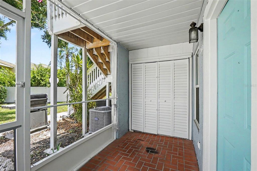 A covered patio with a brick floor, white louvered closet doors, and a teal door — 3606 59TH AVENUE W UNIT 3606, BRADENTON, FL
