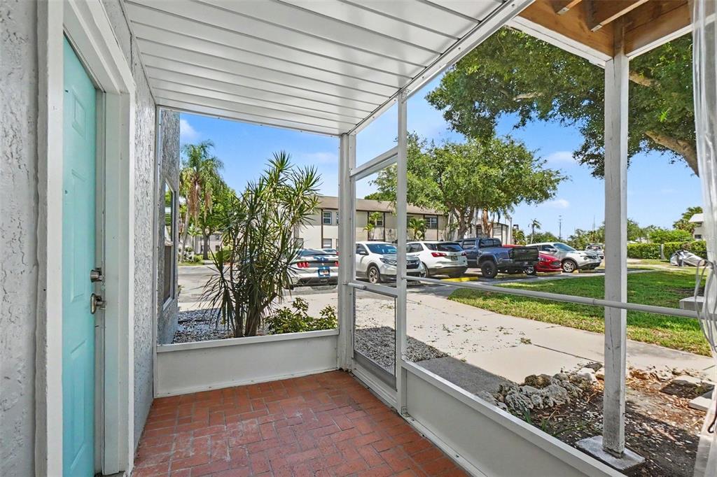 A screened-in porch with brick flooring overlooks a parking lot and apartment buildings — 3606 59TH AVENUE W UNIT 3606, BRADENTON, FL