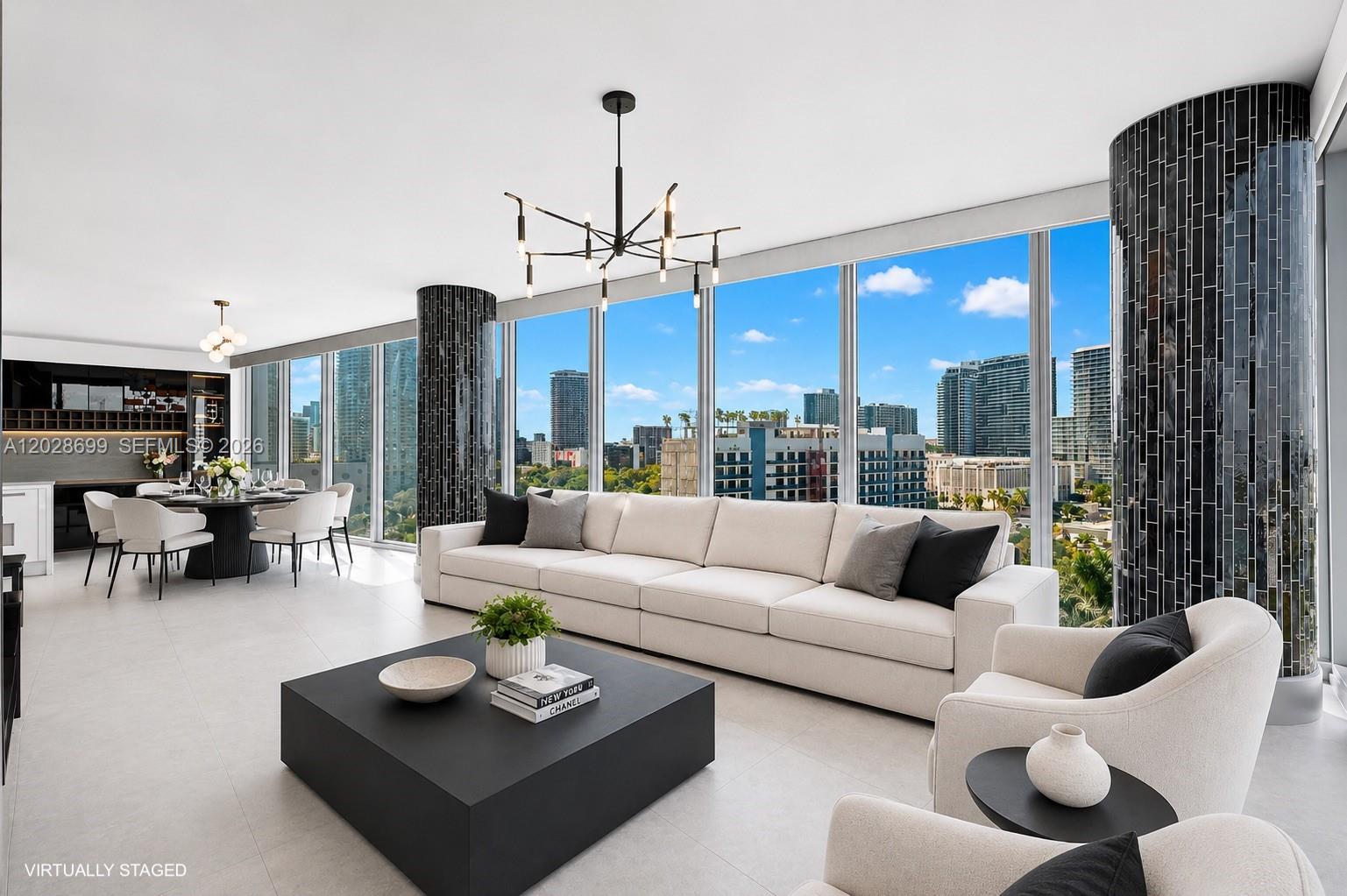 A modern living and dining area features floor-to-ceiling windows, black tiled columns, and neutral furniture — 601 NE 36th St # 1101, Miami FL 33137, MIAMI, FL