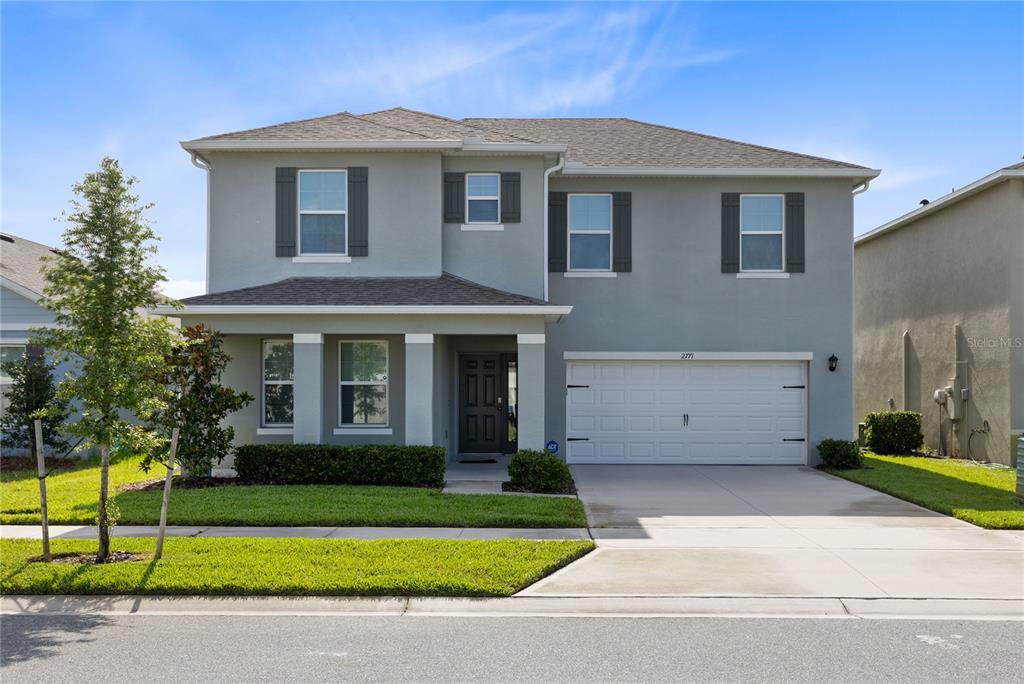 A two-story suburban house with a gray stucco exterior, a two-car garage, and landscaping — 2771 SUNNYVALE STREET, ST CLOUD, FL