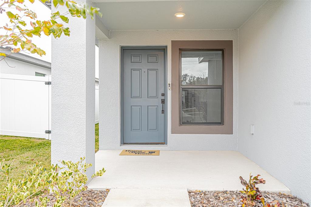 A covered concrete porch leads to a gray front door and a single window — 1375 AHOY AVENUE, TAMPA, FL