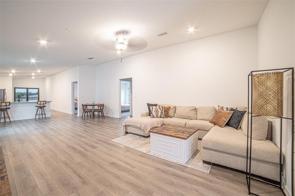 A spacious open-concept living room features light wood-look flooring, a sectional sofa, and recessed lighting — 1375 AHOY AVENUE, TAMPA, FL
