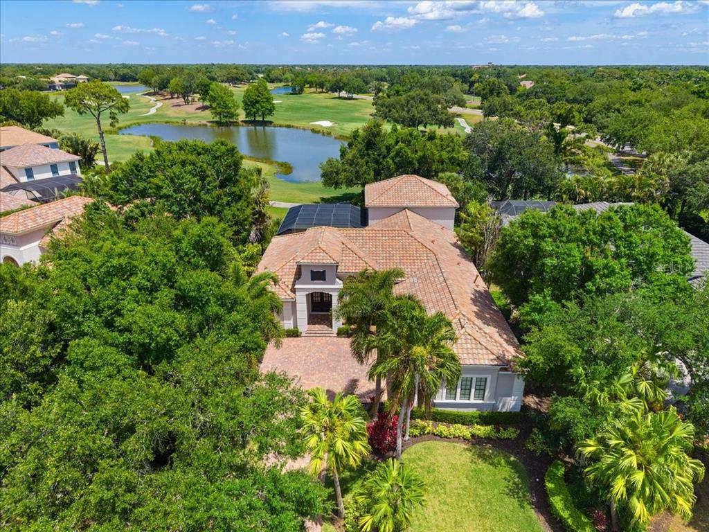 A single-story house with a tiled roof, brick driveway, and lush tropical landscaping — 7527 GREYSTONE STREET, LAKEWOOD RANCH, FL