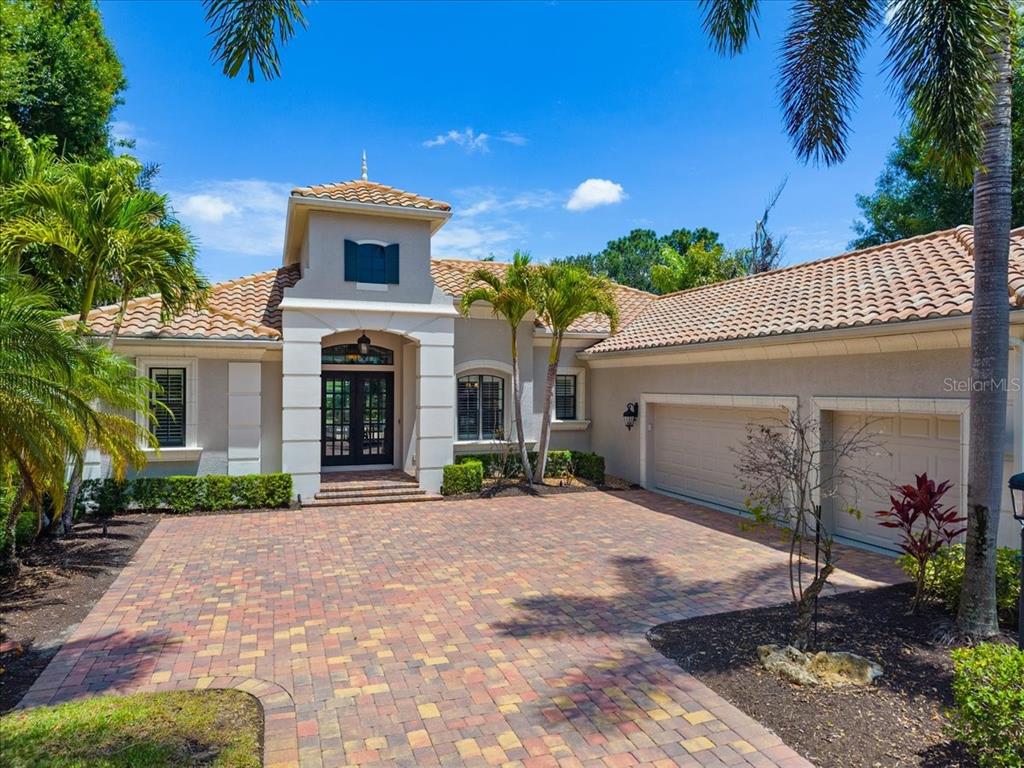 A single-story house with a tiled roof, brick paver driveway, and an attached three-car garage — 7527 GREYSTONE STREET, LAKEWOOD RANCH, FL