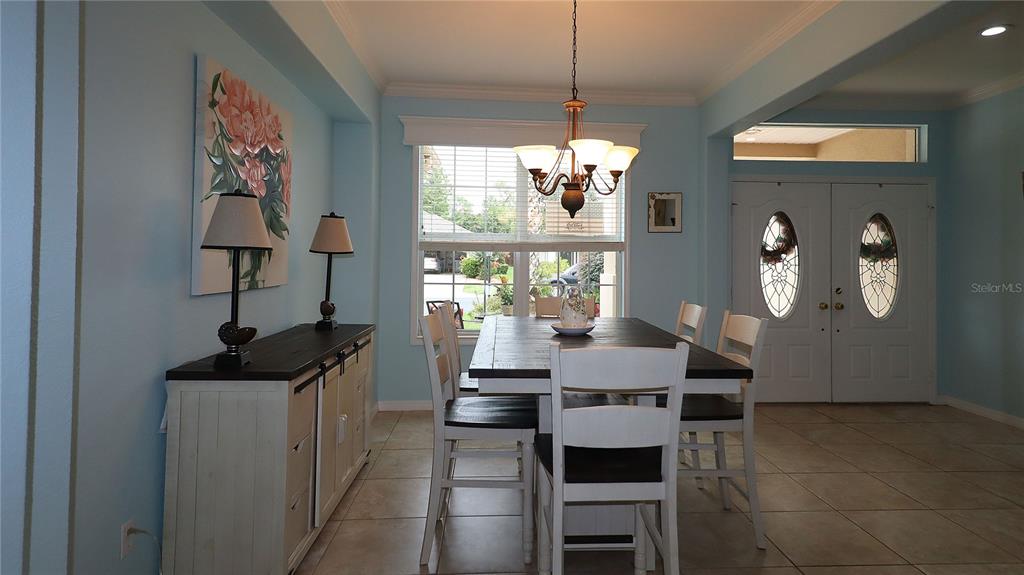 A dining room with a wooden table, white chairs, a sideboard, and light blue walls — 11735 SE 91ST CIRCLE, SUMMERFIELD, FL