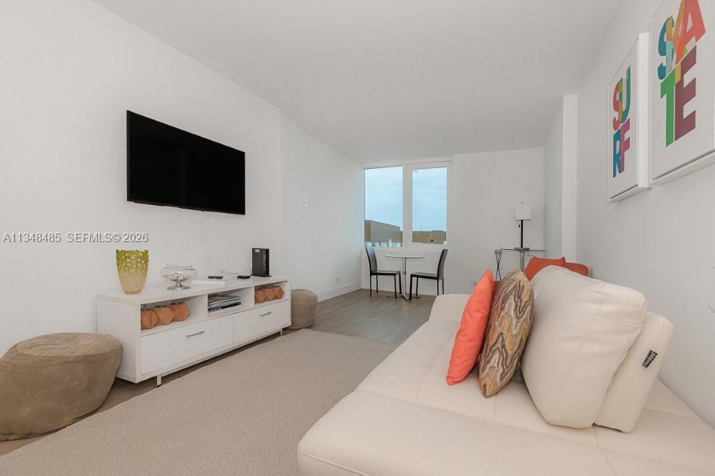 A bright living room features a white sofa, a television, and a small dining area — 2301 Collins Ave # 927, Miami Beach FL 33139, MIAMI BEACH, FL