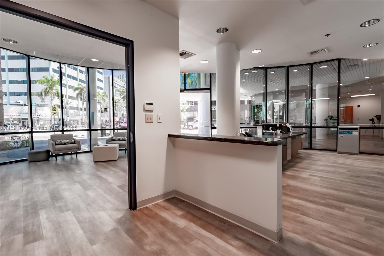A modern office interior features a reception desk, glass partitions, and a seating area — 410 W 41st St # 103, Miami Beach FL 33140, MIAMI BEACH, FL