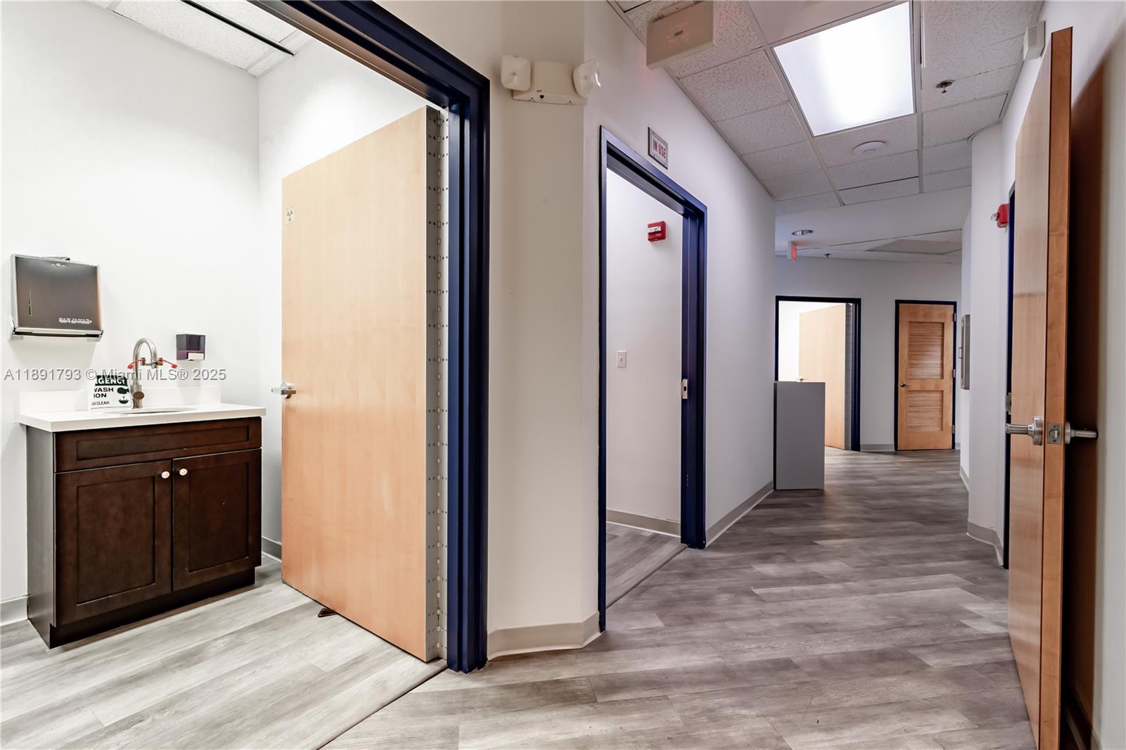 A hallway features light wood-look flooring, multiple doorways, and a small sink area — 410 W 41st St # 103, Miami Beach FL 33140, MIAMI BEACH, FL