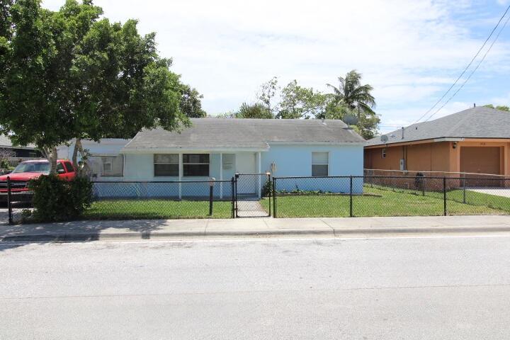 A light blue single-story house with a chain-link fence and a red truck parked outside — 1417 W 32nd Street, Riviera Beach FL 33404, RIVIERA BEACH, FL