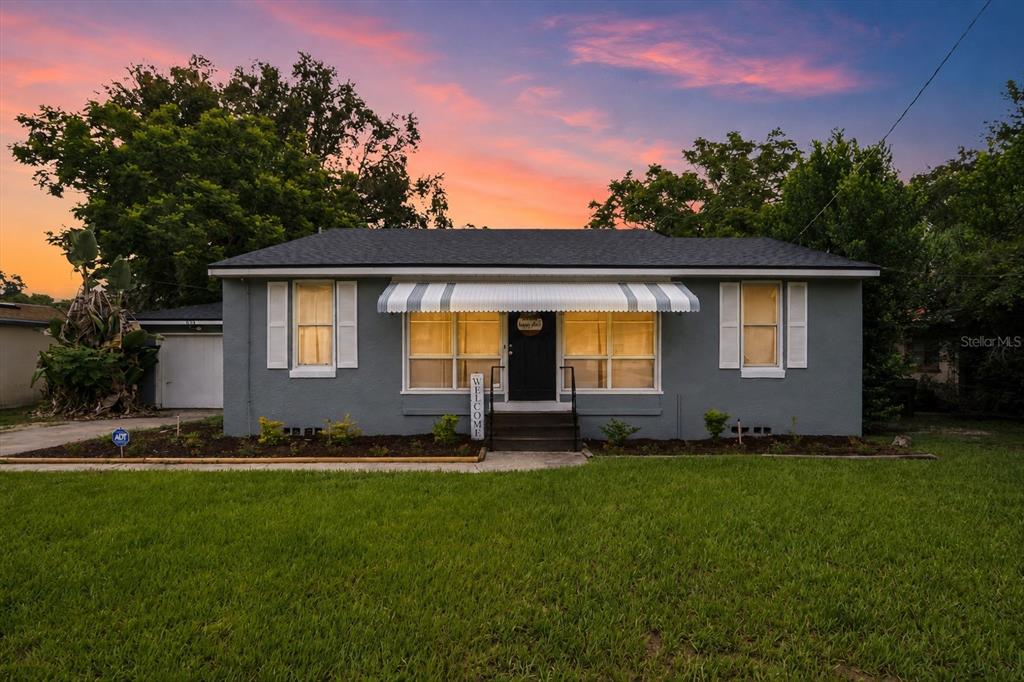 A gray single-story house with a striped awning over the front door and white shutters — 615 AVENUE A NE, WINTER HAVEN, FL