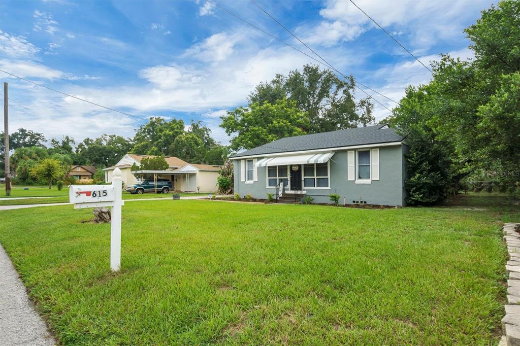 A single-story gray house with a white awning and a mailbox in the front yard — 615 AVENUE A NE, WINTER HAVEN, FL