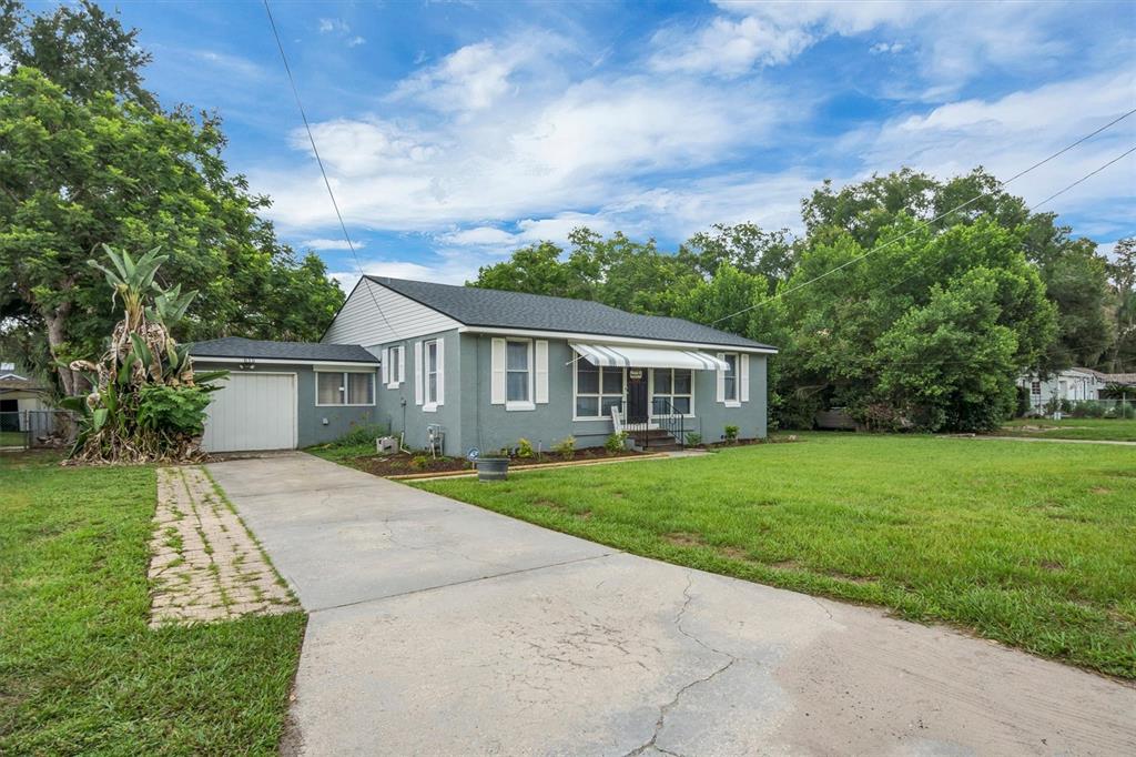 A single-story gray house with a white garage, driveway, and a large front lawn — 615 AVENUE A NE, WINTER HAVEN, FL