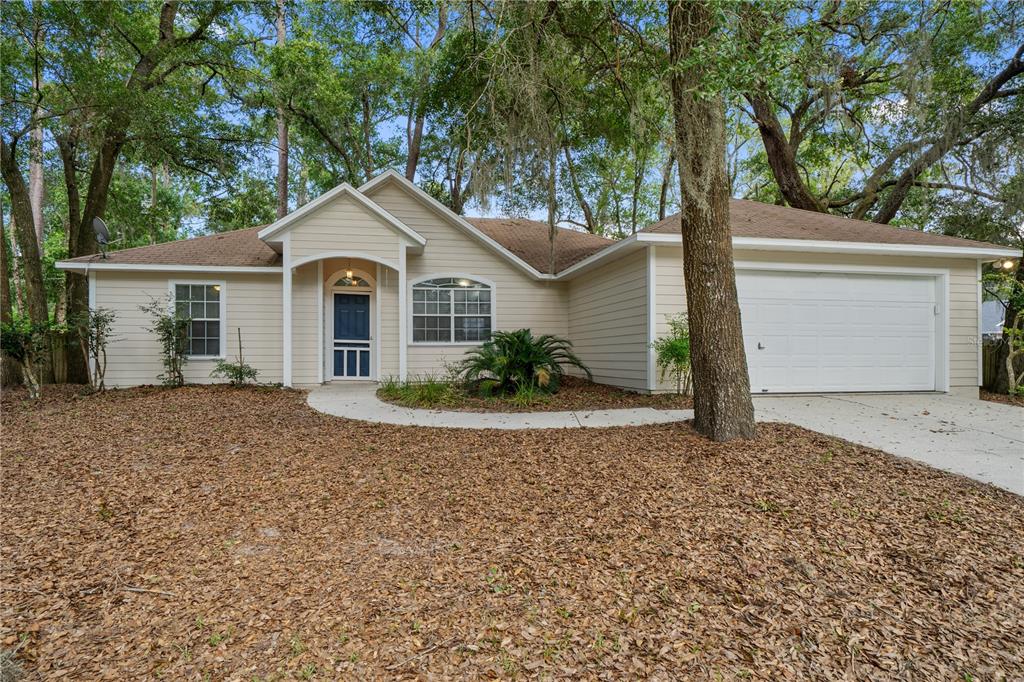 A single-story house with beige siding, a front porch, and an attached two-car garage — 2077 SW 42ND LANE, GAINESVILLE, FL