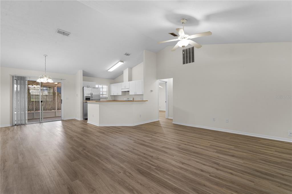 An open-concept living and dining area features vaulted ceilings, wood-look flooring, and a kitchen island — 2077 SW 42ND LANE, GAINESVILLE, FL