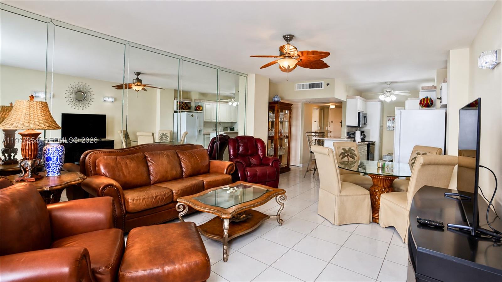 A living room and dining area with leather furniture, tiled floors, and mirrored walls — 100 Lincoln Rd # 422, Miami Beach FL 33139, MIAMI BEACH, FL