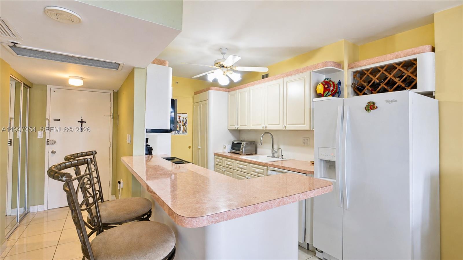 A kitchen features a pink laminate breakfast bar, white cabinets, and a white refrigerator — 100 Lincoln Rd # 422, Miami Beach FL 33139, MIAMI BEACH, FL