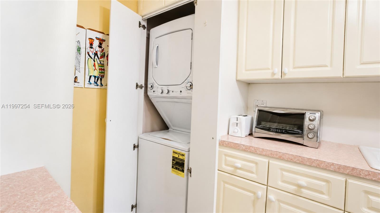 A laundry closet with a stacked washer and dryer sits beside a kitchen counter — 100 Lincoln Rd # 422, Miami Beach FL 33139, MIAMI BEACH, FL