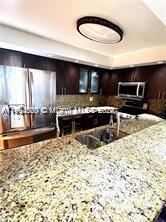 A kitchen features dark wood cabinets, granite countertops, stainless steel appliances, and a circular ceiling light — 800 N Miami Ave # 1501, Miami FL 33130, MIAMI, FL
