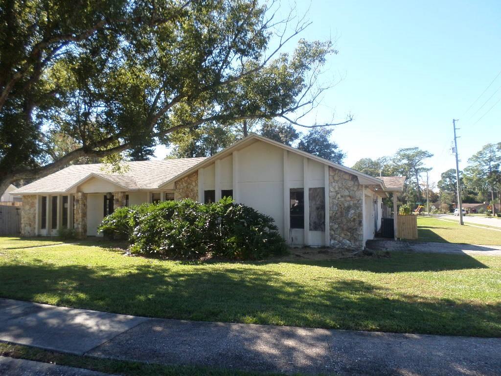 A single-story house with a stone facade, light-colored siding, and a large tree in front — 210 BANBURY COURT, LONGWOOD, FL