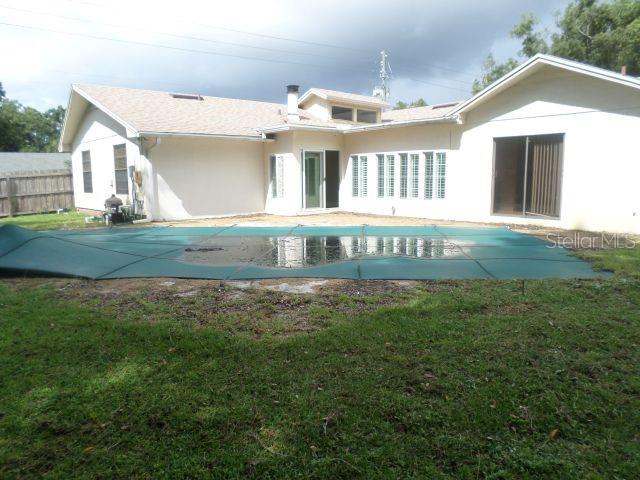 The exterior of a house features a pool covered by a large green safety tarp — 210 BANBURY COURT, LONGWOOD, FL