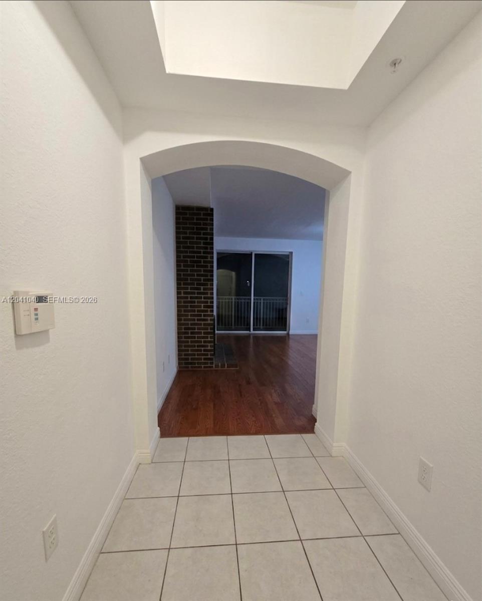 A tiled entryway leads through an arched doorway into a living area with hardwood floors — 8936 W Flagler St # 204, Miami FL 33174, MIAMI, FL