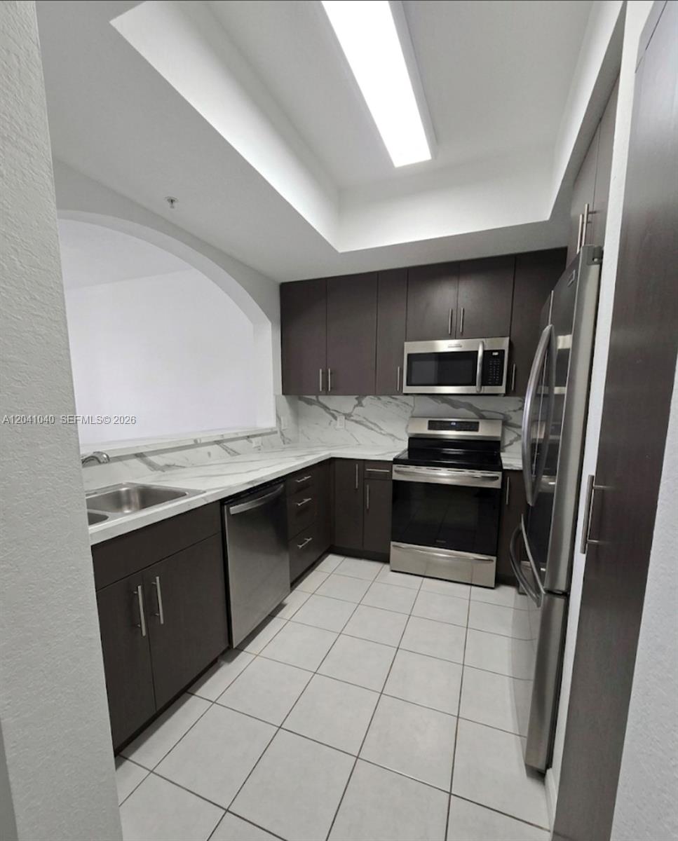 A kitchen features dark wood cabinets, stainless steel appliances, and white marble-patterned countertops — 8936 W Flagler St # 204, Miami FL 33174, MIAMI, FL