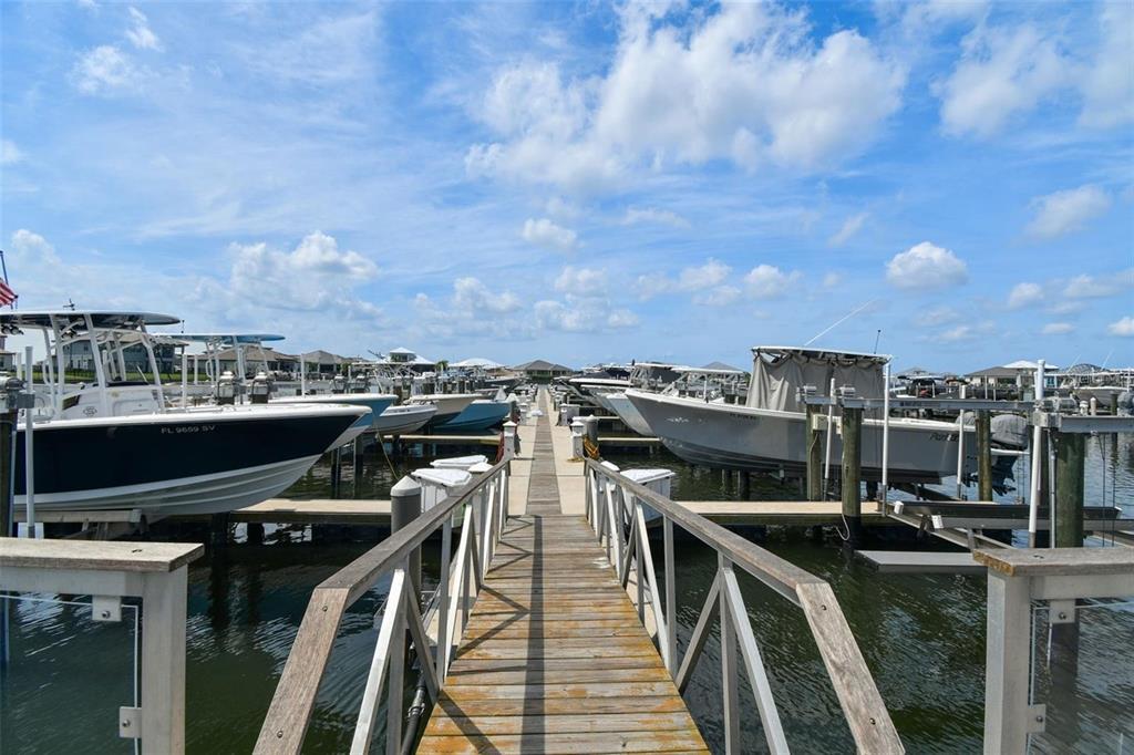 A wooden pier extends between two rows of boats docked in a marina — 1802 5TH STREET E, PALMETTO, FL