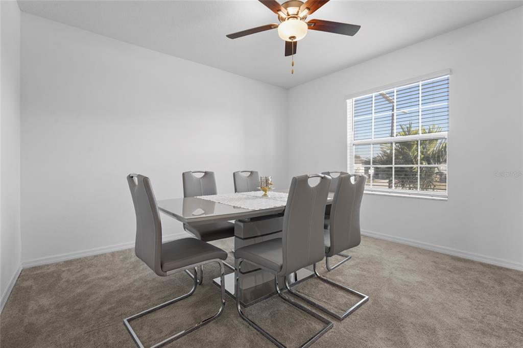 A dining room features a modern table with six gray chairs and a ceiling fan — 4016 86TH STREET E, PALMETTO, FL