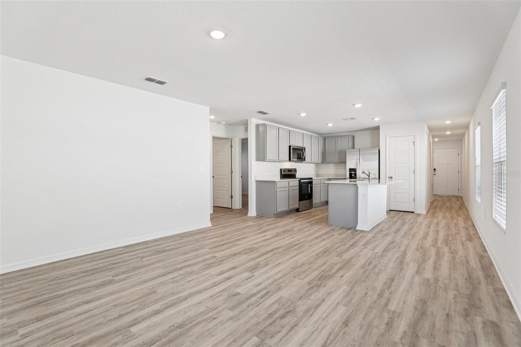An open-concept kitchen and living area feature light wood-look flooring and grey cabinetry — 1193 CUMBERLAND TRAIL DRIVE, LAKE HAMILTON, FL
