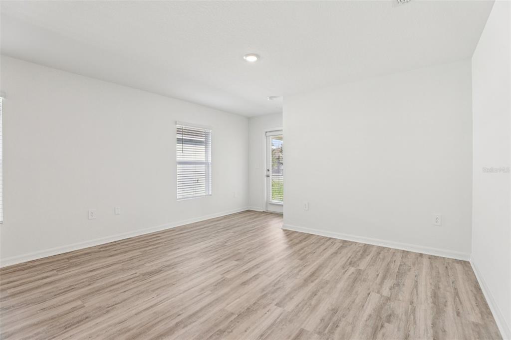 An empty room with white walls, light wood-look flooring, a window, and a glass door — 1193 CUMBERLAND TRAIL DRIVE, LAKE HAMILTON, FL