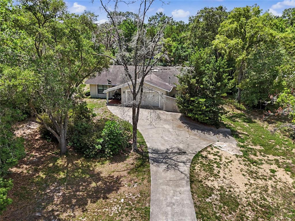 An aerial view shows a single-story house with a concrete driveway surrounded by dense trees — 20250 SW 93 LANE ROAD, DUNNELLON, FL