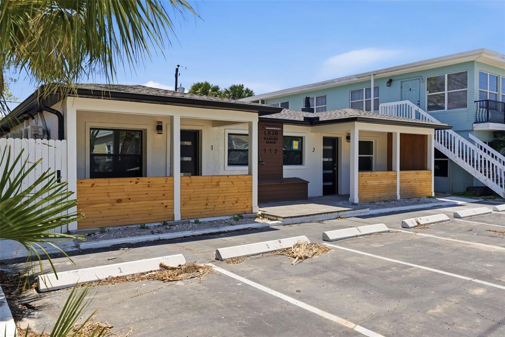 A single-story building with two numbered units features wood-paneled porches and a paved parking lot — 113 145TH AVENUE E UNIT 4, MADEIRA BEACH, FL