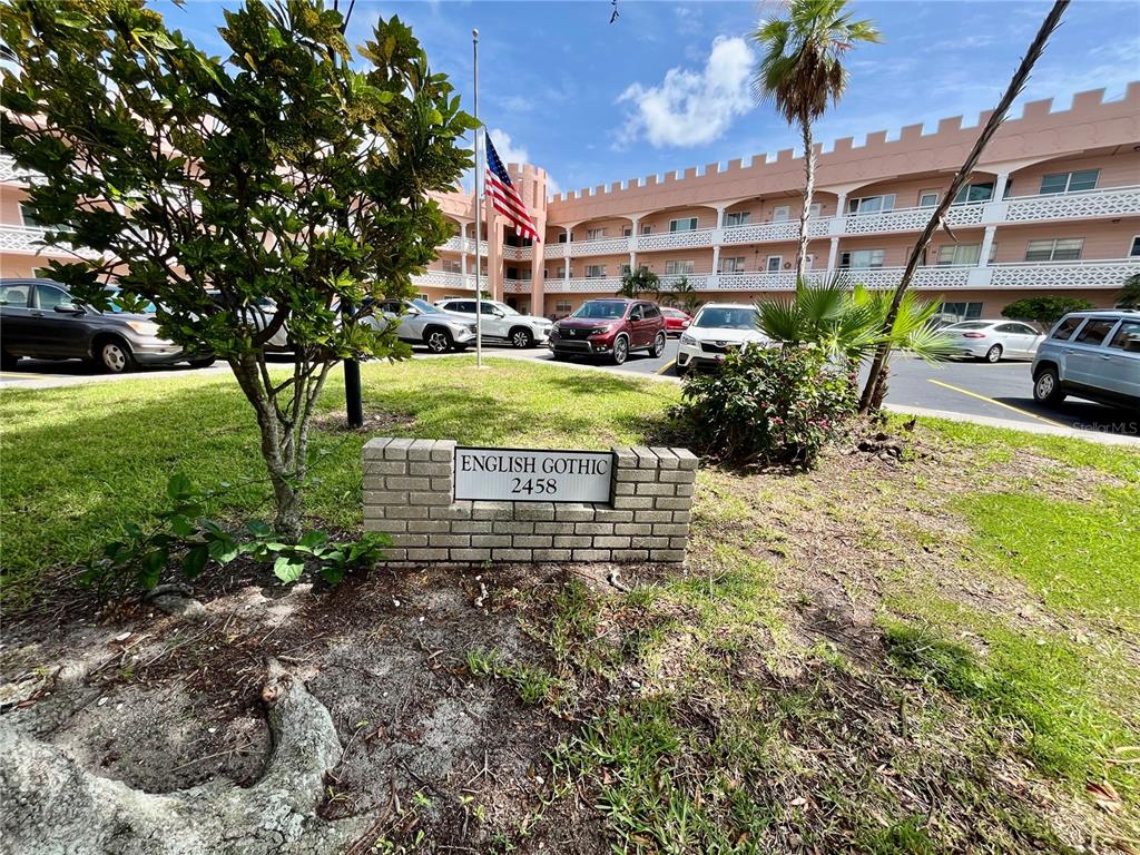 A brick sign labeled English Gothic 2458 sits in front of a pink castle-themed apartment building — 2458 COLUMBIA DRIVE UNIT 28, CLEARWATER, FL