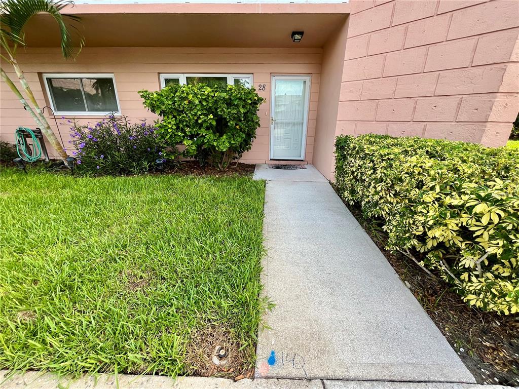 A pink exterior building features a front door numbered 28, a walkway, and landscaping — 2458 COLUMBIA DRIVE UNIT 28, CLEARWATER, FL
