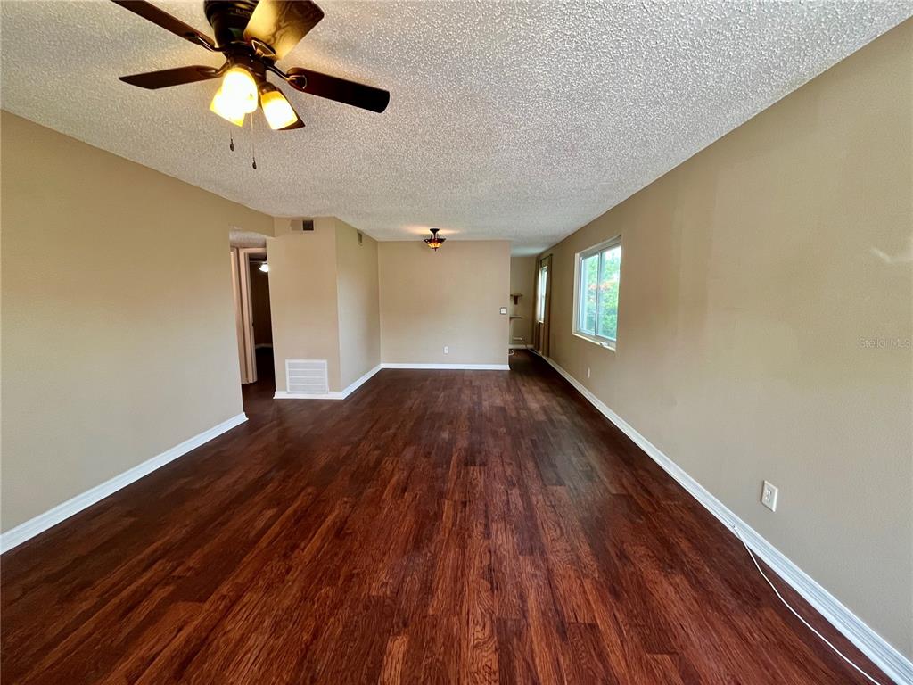 An empty room with dark wood-look flooring, beige walls, and a popcorn ceiling — 2458 COLUMBIA DRIVE UNIT 28, CLEARWATER, FL