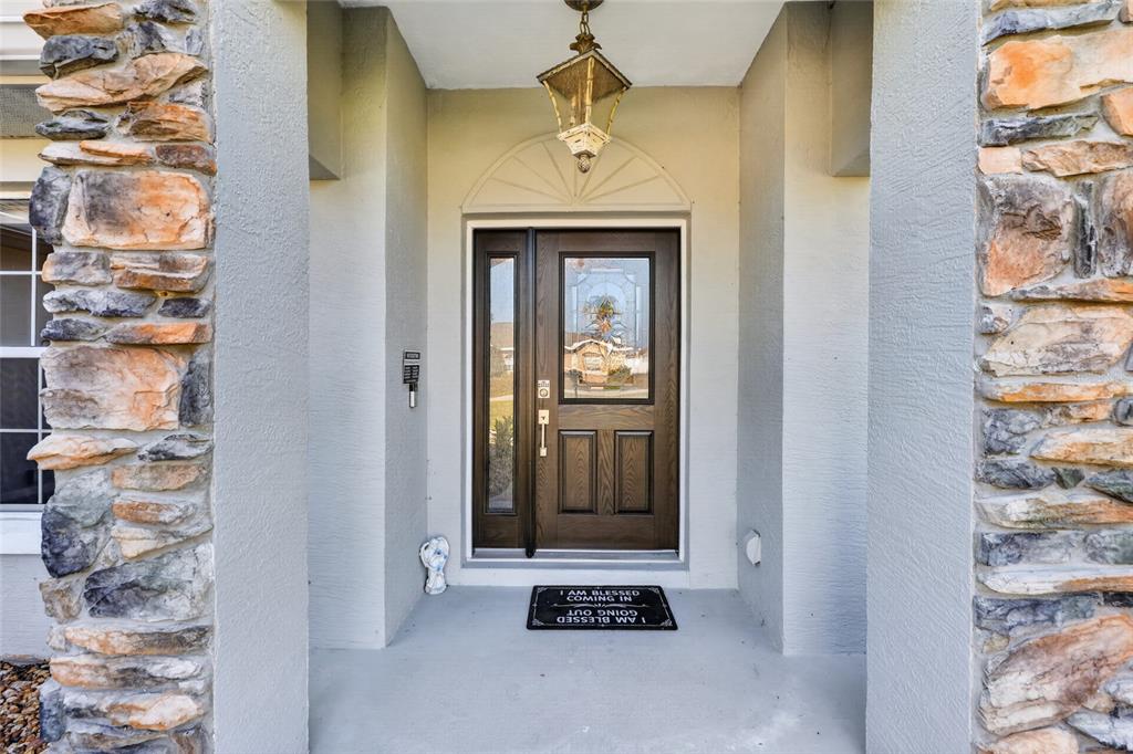 A front entryway features a dark wood door with glass panels and stone-veneer columns — 9583 SW 46TH TERRACE, OCALA, FL