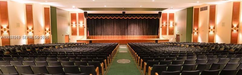 A large auditorium features rows of dark seating facing a stage with a black curtain — PEMBROKE PINES, FL