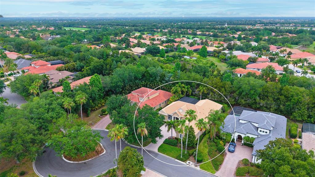 An aerial view of a suburban house with a tan tile roof and palm trees — 7507 ABBEY GLEN, BRADENTON, FL