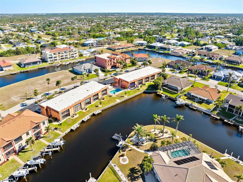 An aerial view shows two multi-story buildings with pools situated along a canal — 1345 MEDITERRANEAN DRIVE UNIT A105, PUNTA GORDA, FL
