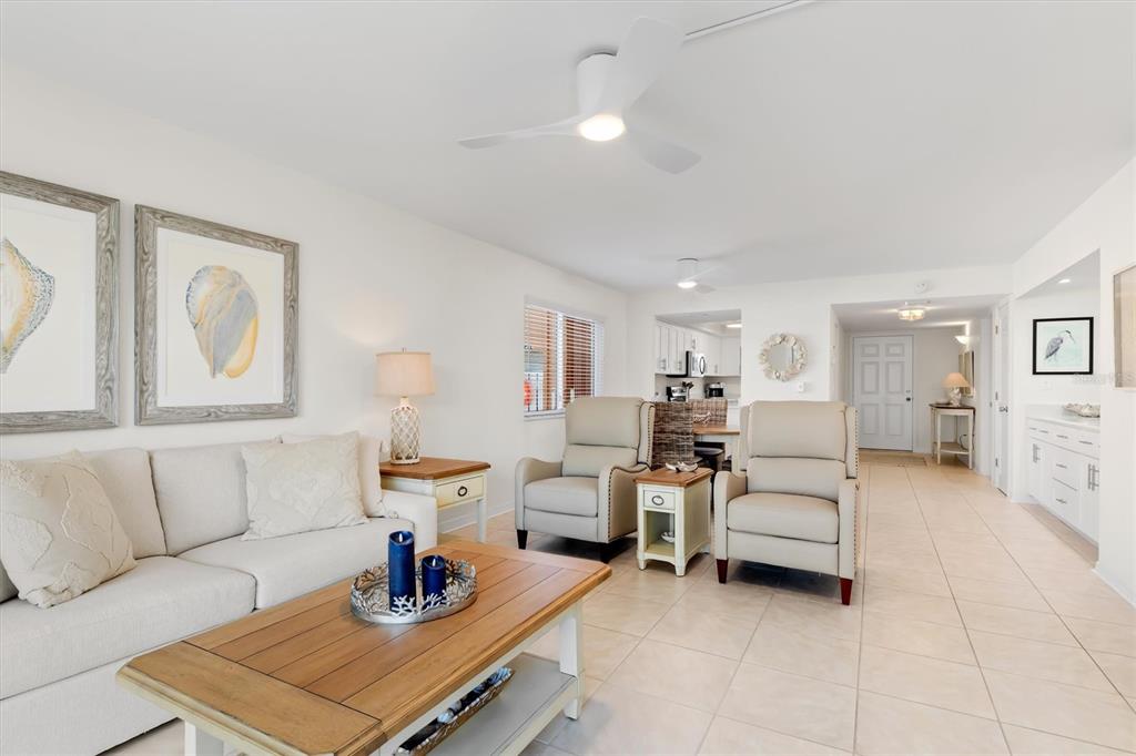 A living room features a beige sofa, two armchairs, a wooden coffee table, and tile flooring — 1345 MEDITERRANEAN DRIVE UNIT A105, PUNTA GORDA, FL